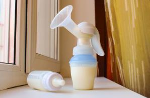 A photograph of a baby bottle filled with milk attached to a breast pump attachment