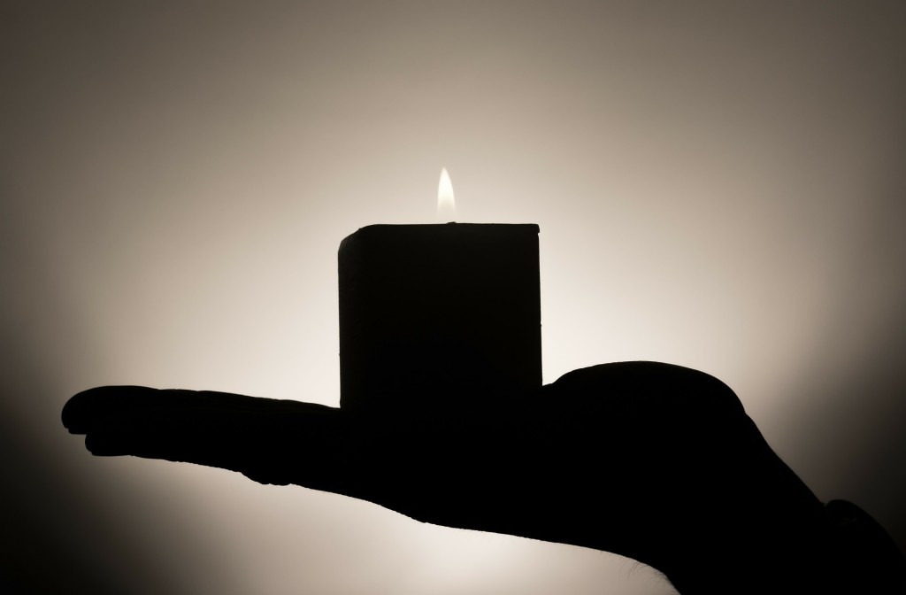 outstretched hand holding a candle